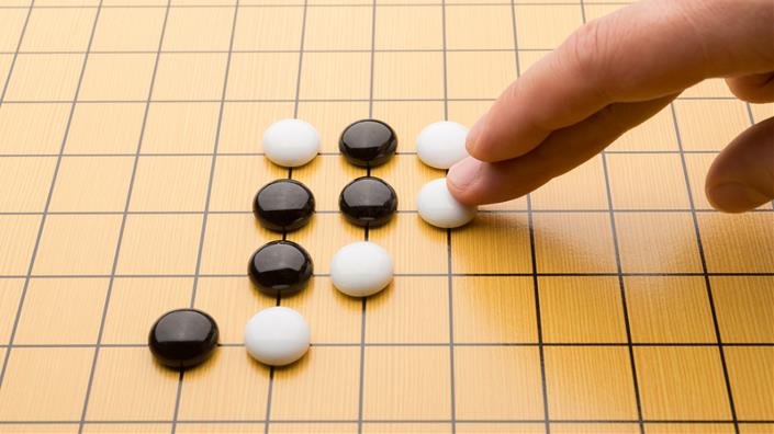 A human player moves a piece during a game of Go (Credit: iStock)