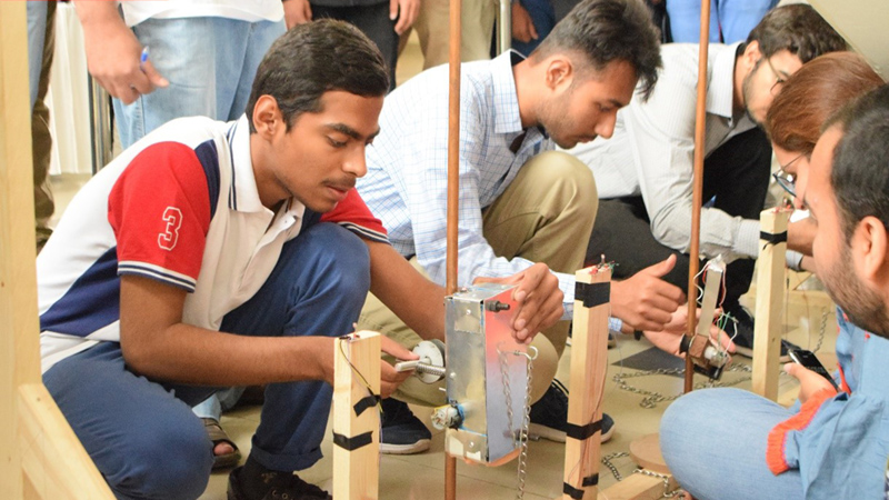 Team representatives setting up their device for the heat. The laser based time measurement system can be seen mounted on the wooden column