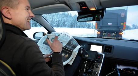 The driver of the car behind the truck drank coffee and read a newspaper Article image
